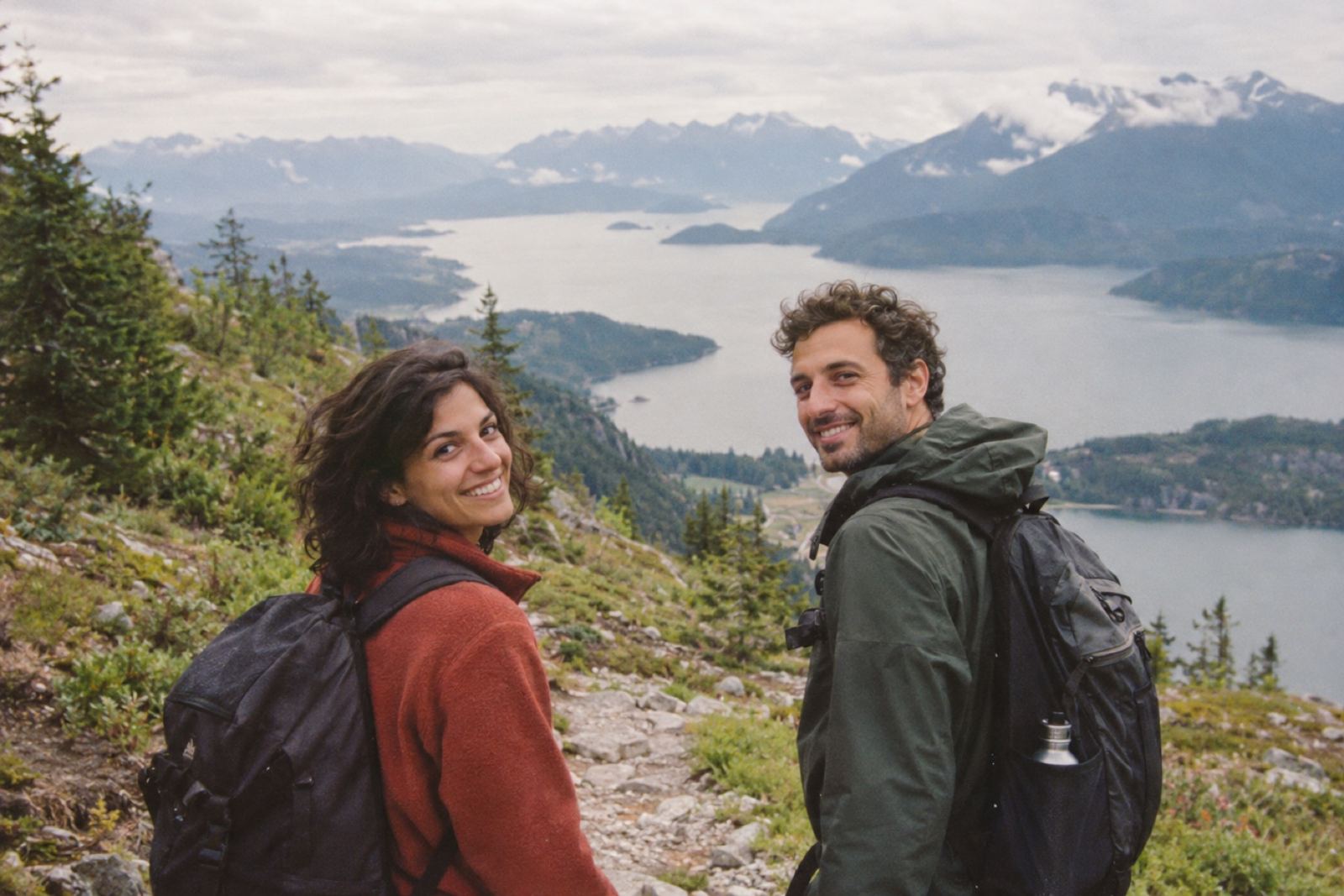Josefina y Tomás haciendo trekking frente a un lago entre montañas